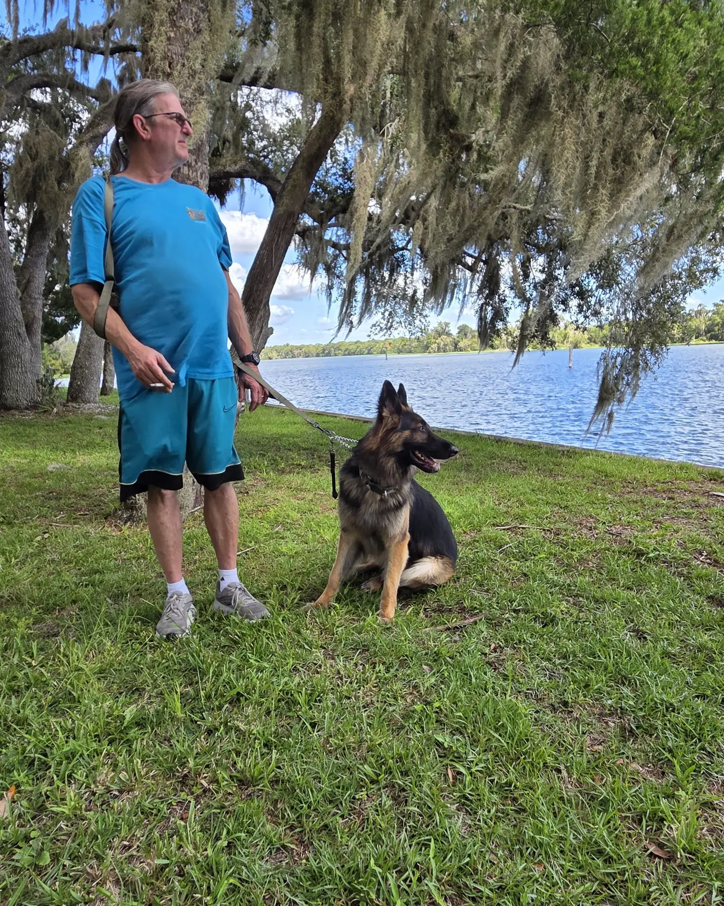 Ken Knorr standing by the lake with his German Shepherd, Gunny